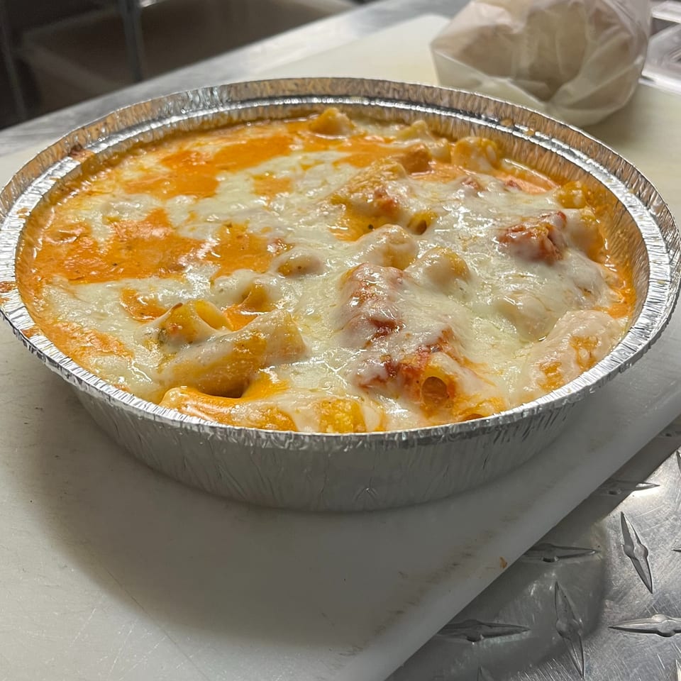 Baked ziti pasta with melted cheese and red sauce in a foil container from Sofia Pizza.